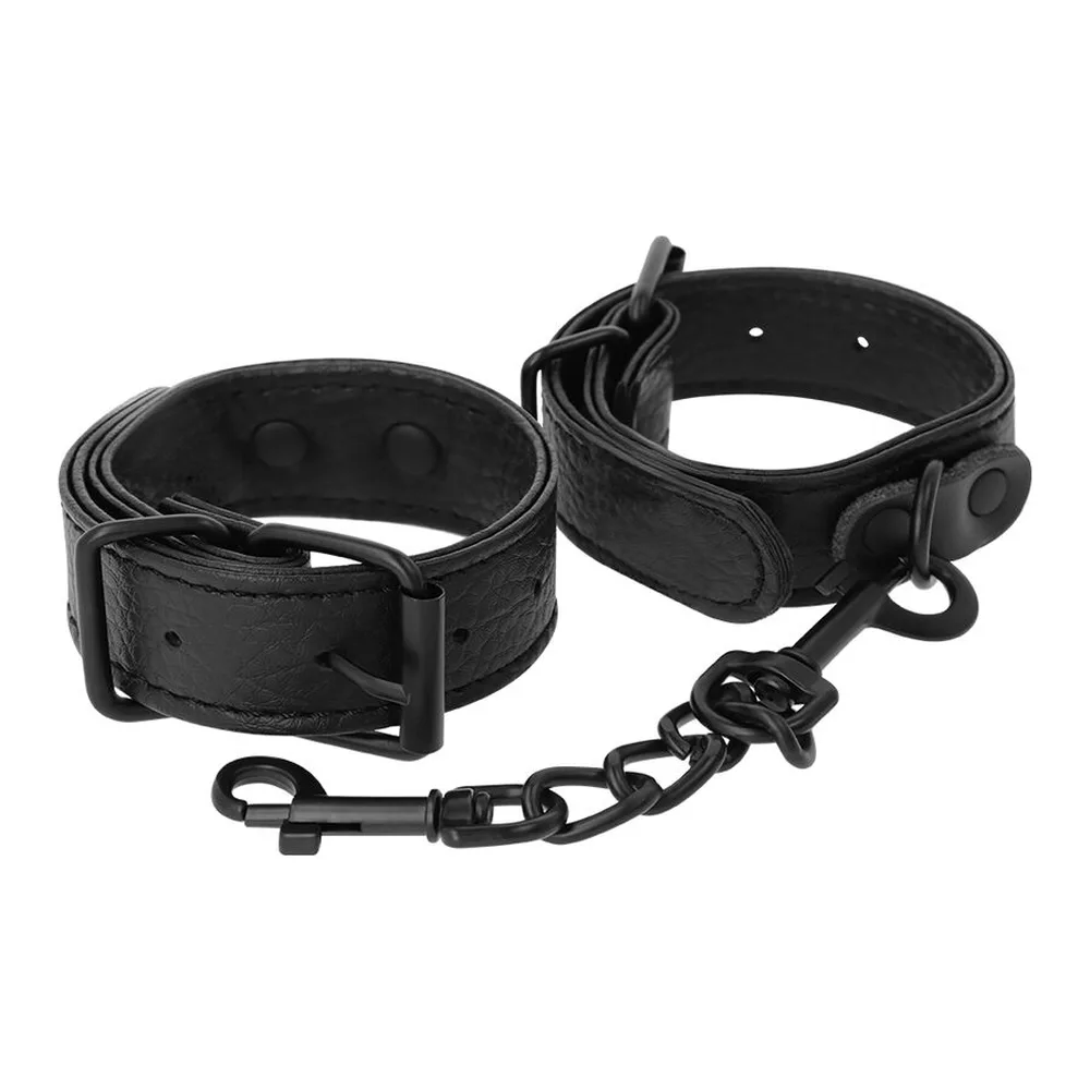 Deux menottes en cuir noir texturisé avec boucles à ardillon métalliques et trous d'ajustement, présentées en diagonale sur fond blanc