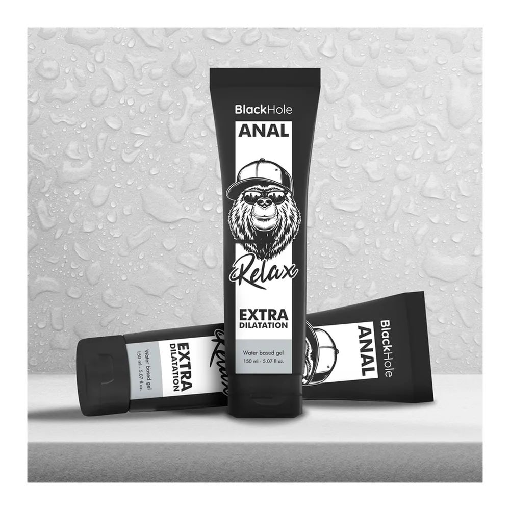 Tube noir de lubrifiant posé dans une main ouverte, gel transparent s'écoulant du tube, avec étiquette blanche indiquant « Extra Dilatation » et icônes de dilatation et relaxation