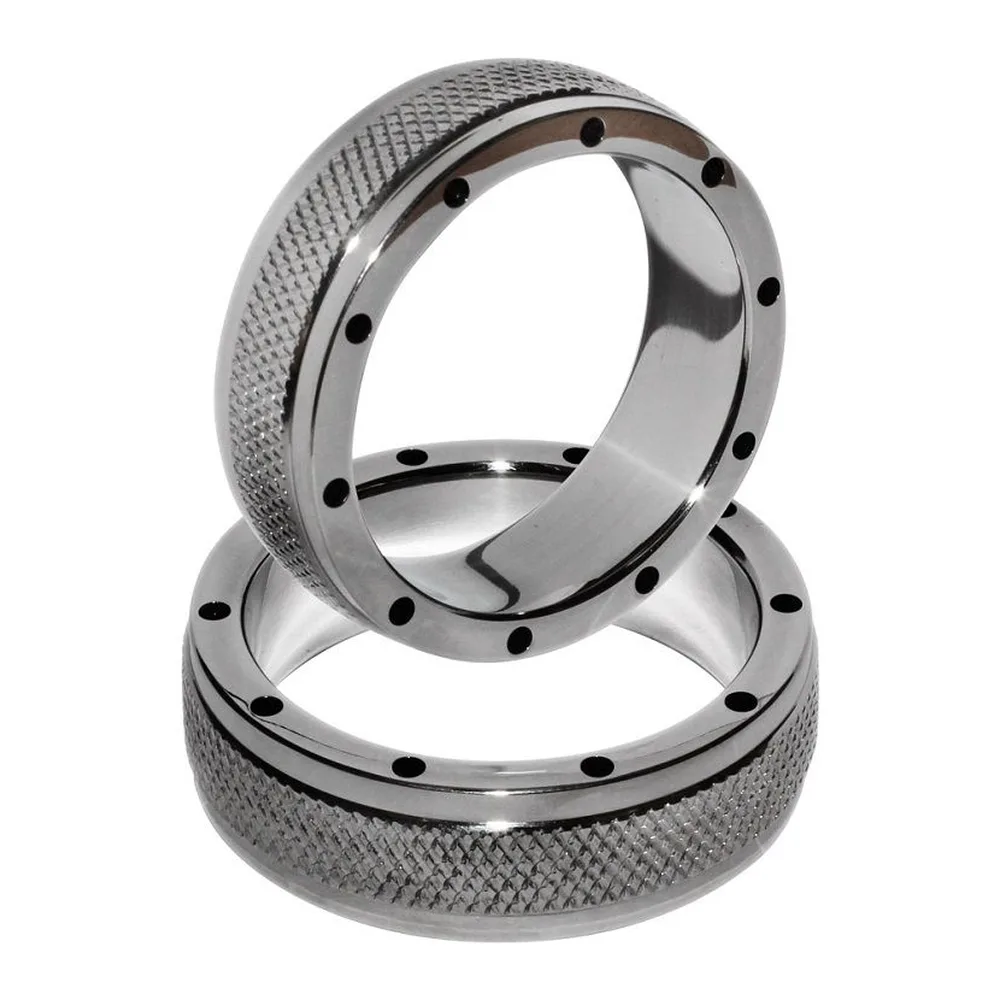 Cockring en acier inoxydable massif avec surface texturée en damier et onze trous noirs espacés régulièrement, présenté en deux tailles empilées sur fond blanc