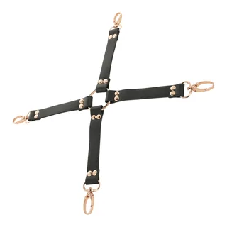 Cravate de suspension en cuir noir avec quatre bras formant une croix, ornée de rivets dorés et quatre mousquetons en métal doré aux extrémités, sur fond blanc