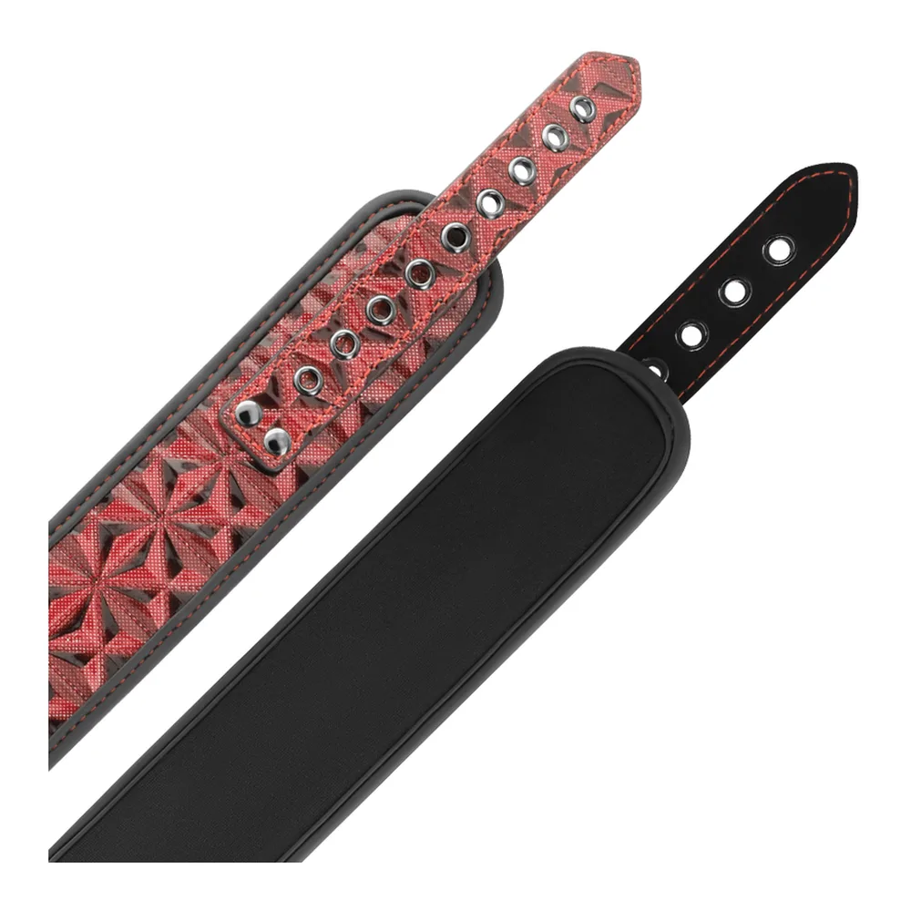 Collier large en simili-cuir rouge motifs noirs avec intérieur doublé noir, doté de deux chaînes métalliques reliées à deux pinces à tétons noires, sur fond blanc