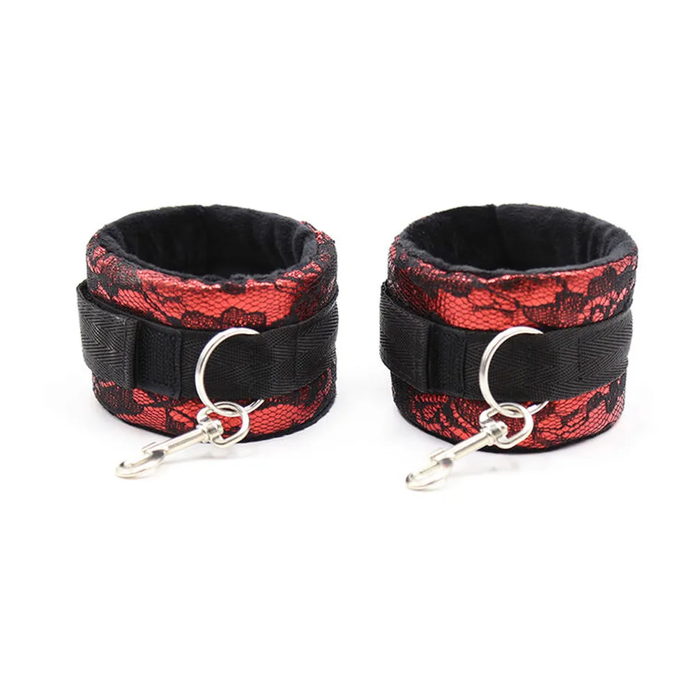 Paire de menottes en velours rouge à motif dentelle noire avec bandes nylon noir et anneaux argentés, sur fond blanc