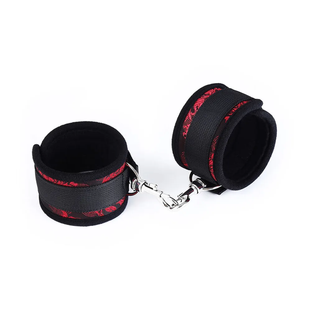 Paire de menottes de poignet en tissu noir avec détails rouges, rembourrées, reliées par une chaîne argentée