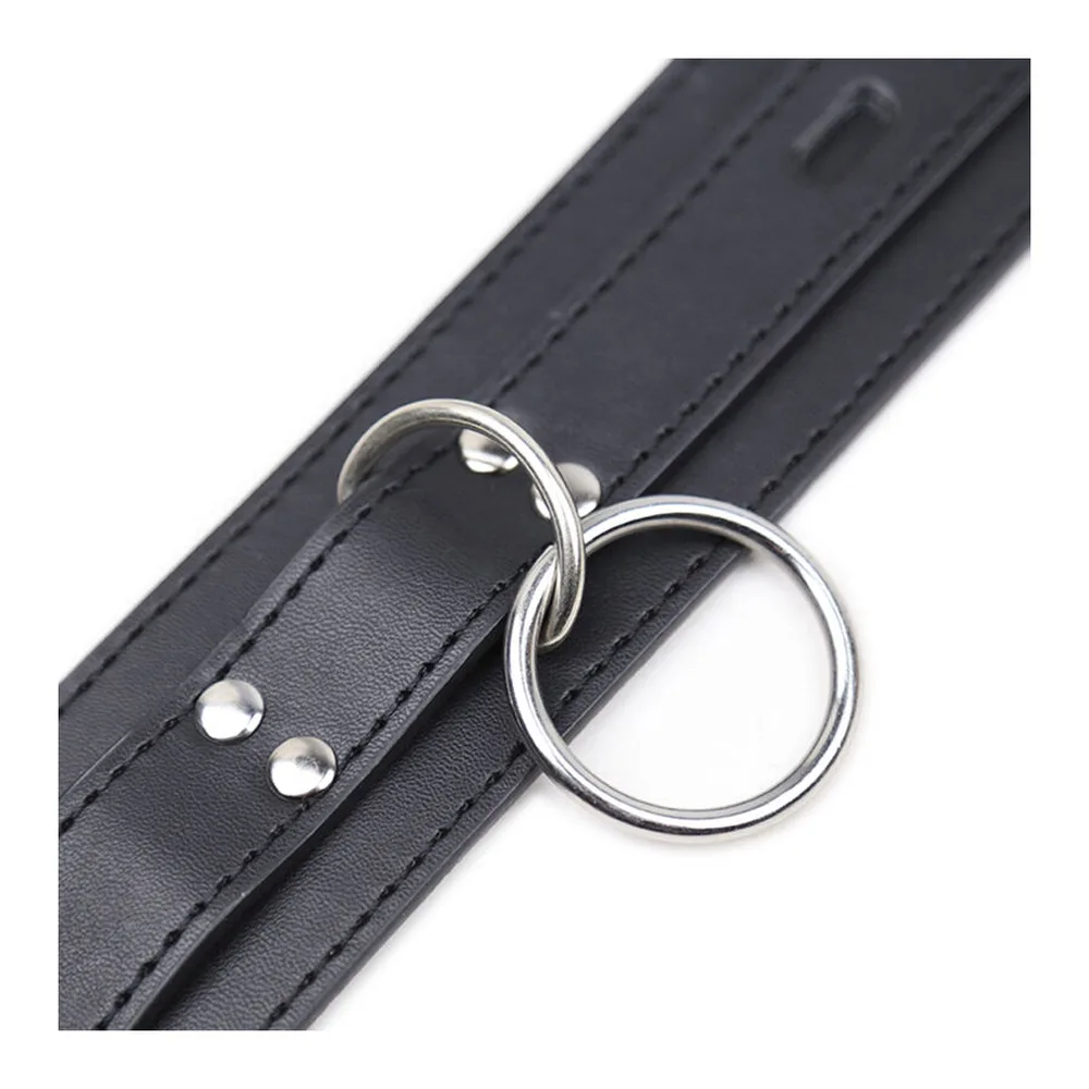 Collier de soumission en cuir noir avec boucle argentée et trois anneaux métalliques, surpiqûres visibles, fond blanc