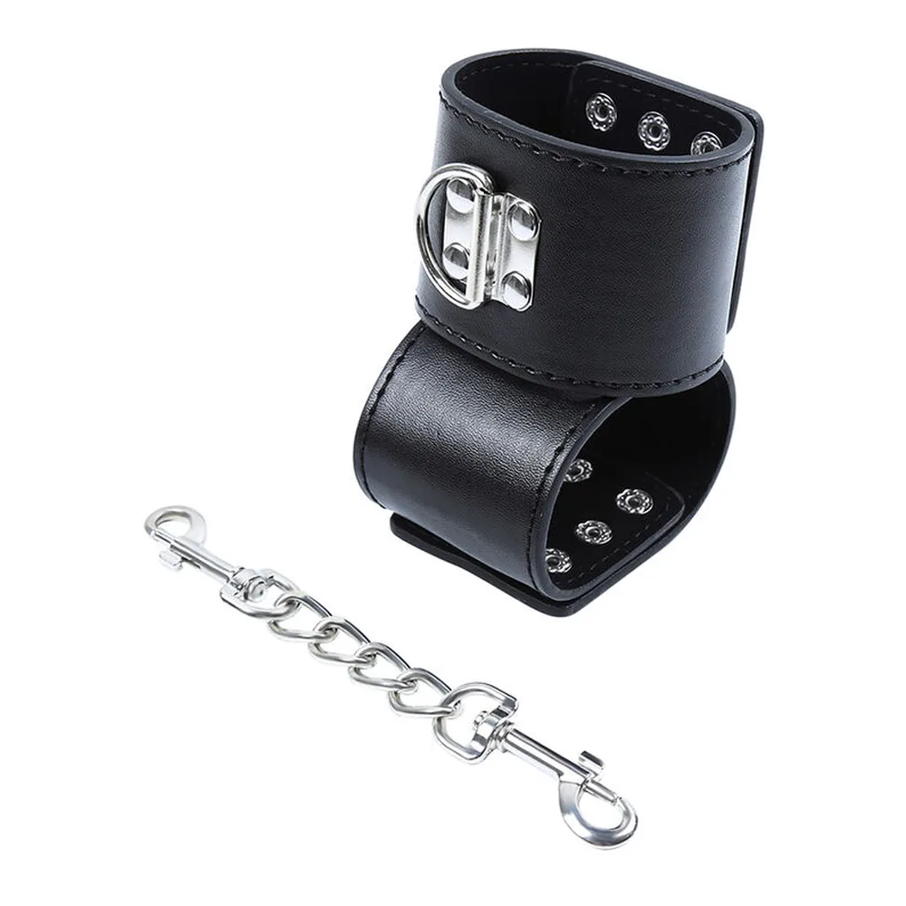 Manchette de poignet noire en cuir synthétique avec fermoir métal argenté, cloutée de rivets, accompagnée de sa chaîne de connexion en métal