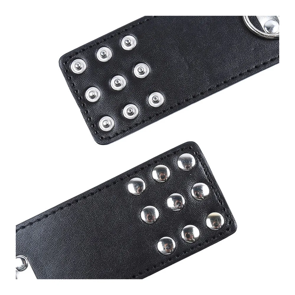 Manchette de poignet noire en cuir synthétique avec fermoir métal argenté, cloutée de rivets, accompagnée de sa chaîne de connexion en métal