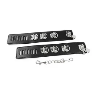 Paire de retenues chevilles en cuir noir avec fermoirs métalliques argentés, fentes de ventilation, anneaux de chaîne et cadenas, présentée avec chaîne de rallonge métallique