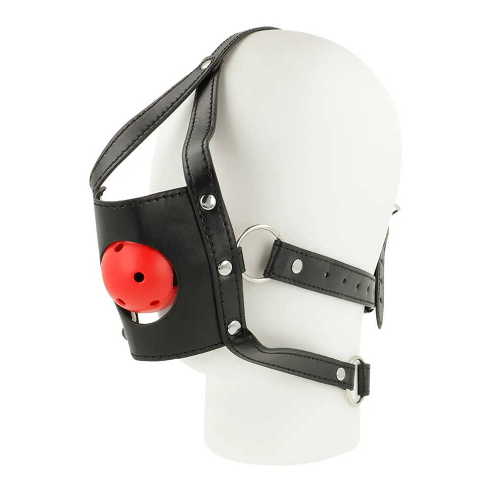 Harnais de tête en cuir noir avec sangles cloutées, muselière ouverte et bâillon boule rouge perforé, présenté sur mannequin blanc