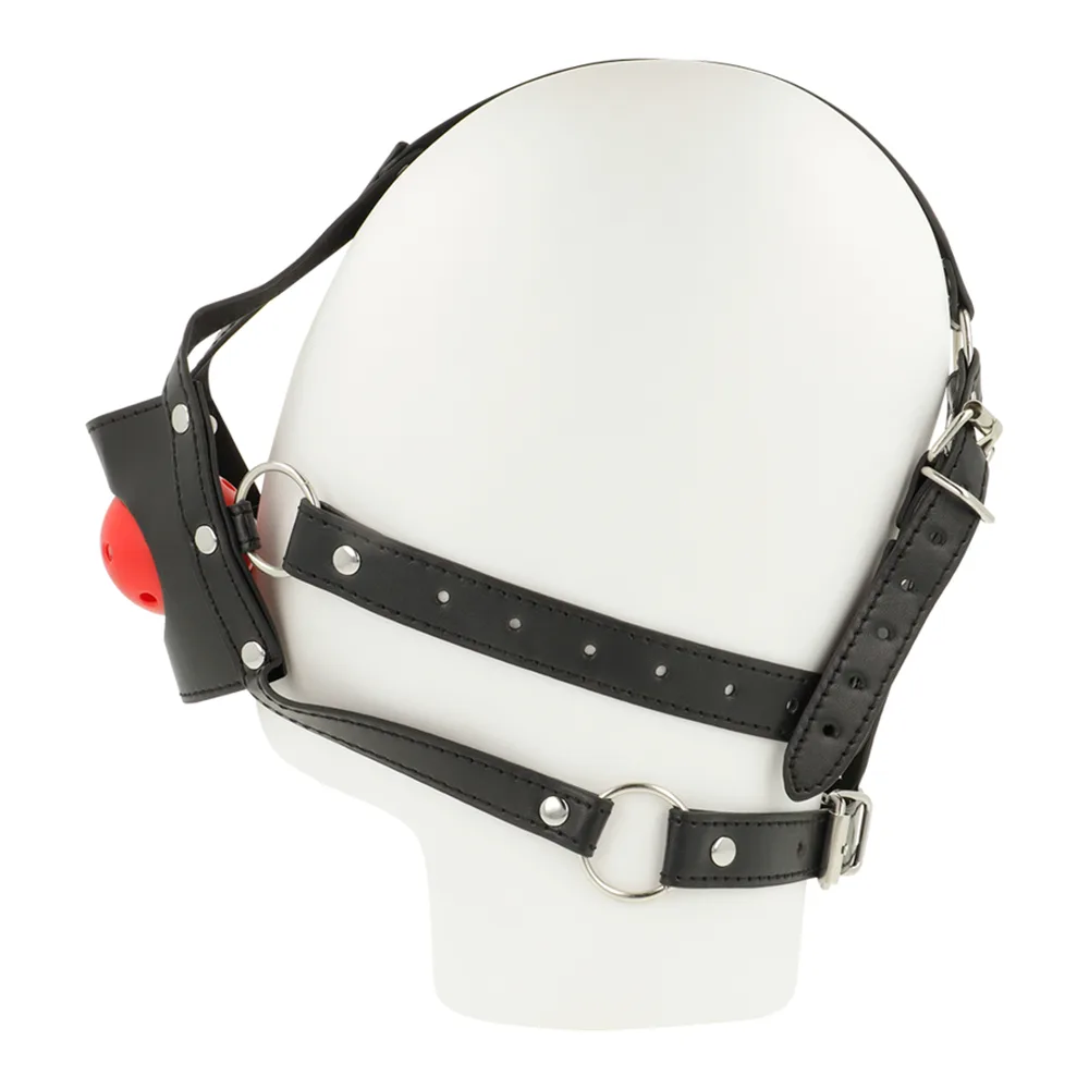Harnais de tête en cuir noir avec sangles cloutées, muselière ouverte et bâillon boule rouge perforé, présenté sur mannequin blanc