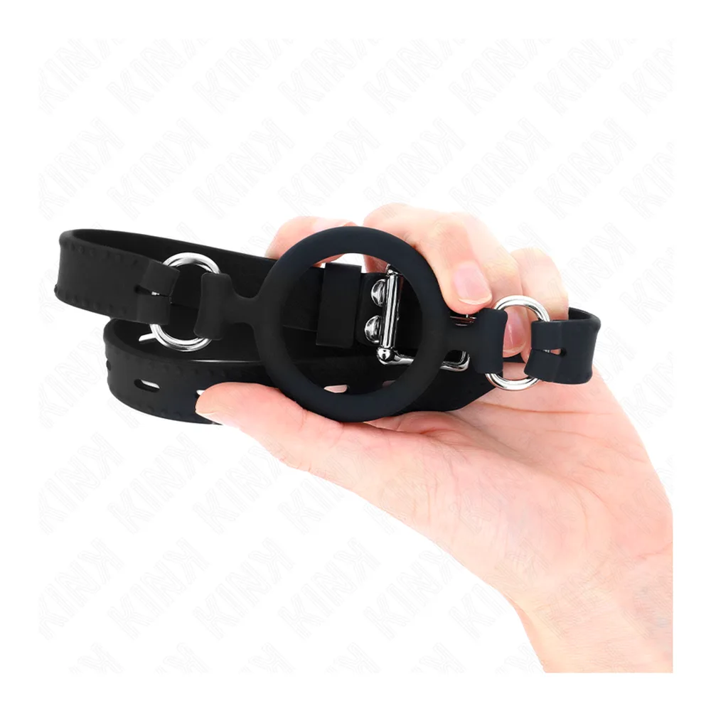 Bâillon à anneau silicone noir avec sangle perforée ajustable et boucles de fixation métalliques, sur fond blanc