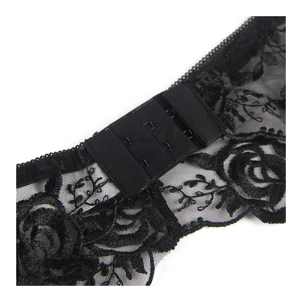 Ensemble trois pièces en dentelle noire florale : soutien-gorge à armatures, string et porte-jarretelles avec détails ajourés, porté sur fond blanc