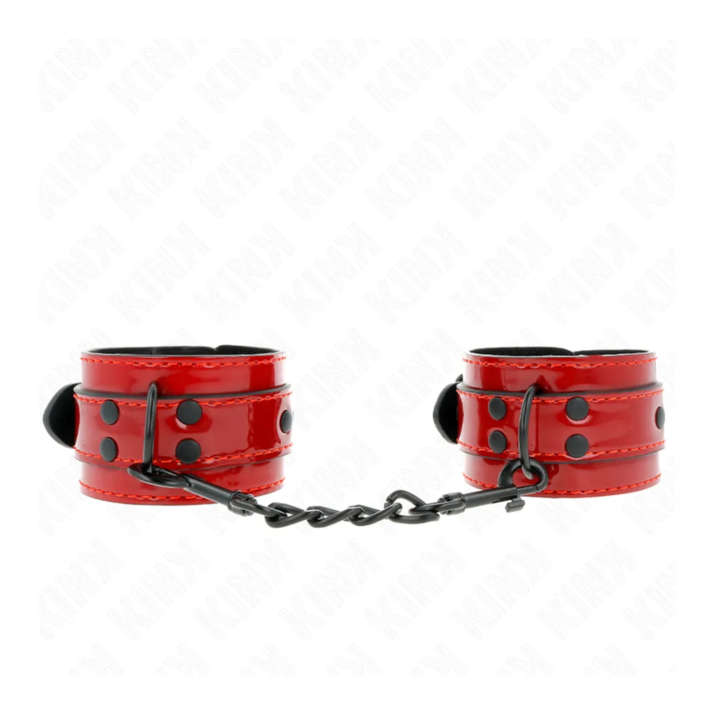 Paire de menottes en cuir verni rouge avec rivets noirs, chaîne acier noir, fermoirs à boucle, sur fond blanc