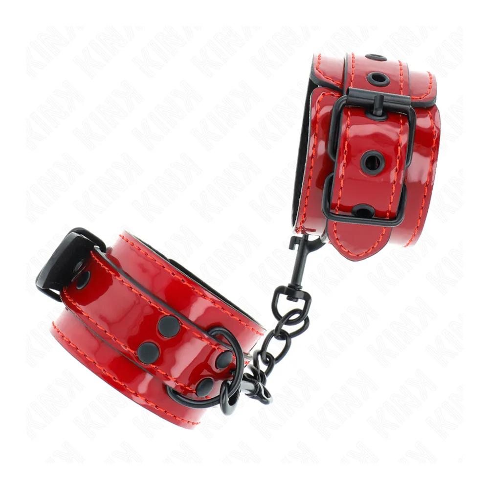 Paire de menottes en cuir verni rouge avec rivets noirs, chaîne acier noir, fermoirs à boucle, sur fond blanc