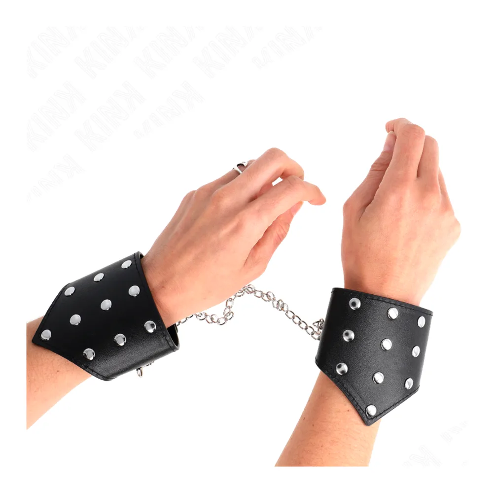Paire de bracelets en cuir noir avec studs métalliques argent, reliés par une chaîne, fond blanc