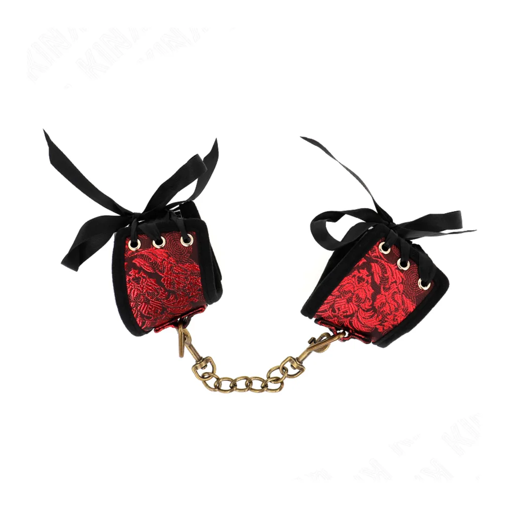 Attache-poignets en dentelle rouge avec revers noir, ornements en laiton, chaîne dorée et anneau de suspension, sur fond blanc