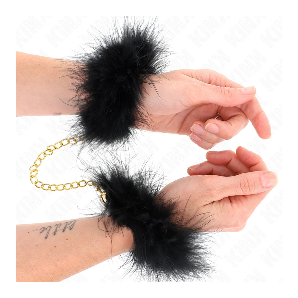 Paire de manchettes en plumes noires fluffies reliées par une fine chaîne dorée, sur fond blanc