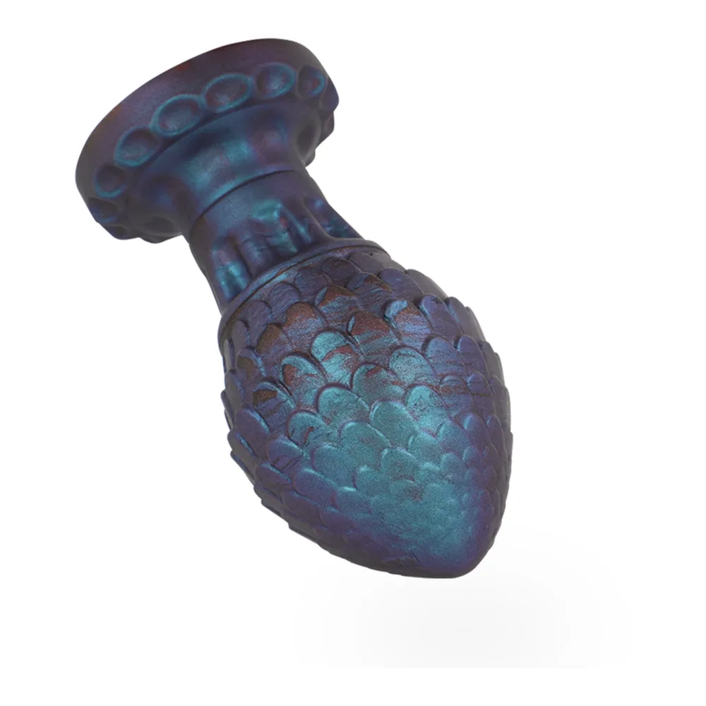 Plug anal en silicone en forme d'œuf de dragon, bleu et violet avec écailles en relief et patine turquoise, base évasée, sur fond blanc