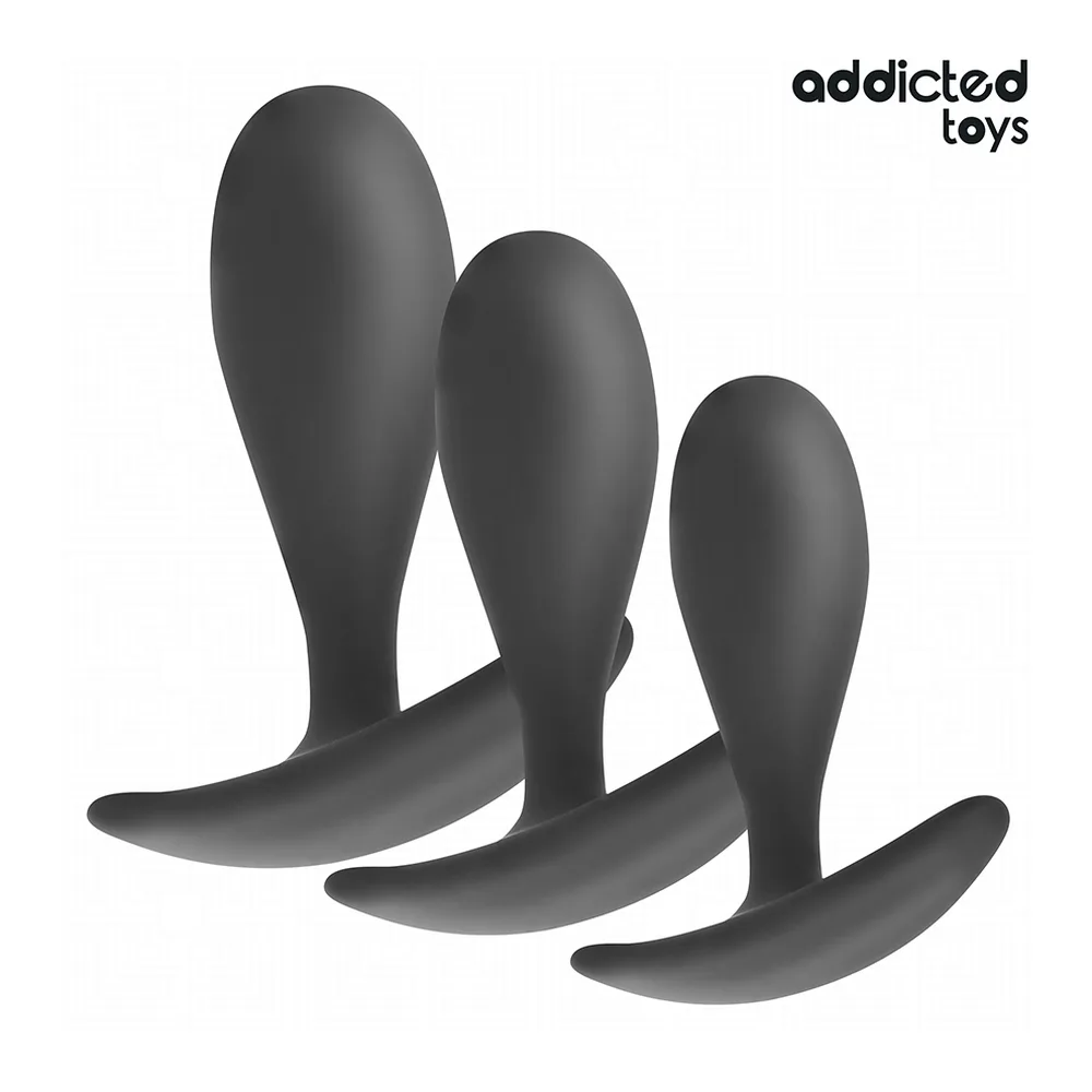 Plug anal noir en silicone tenu dans une main ouverte sur fond blanc, montrant sa forme effilée et sa base élargie