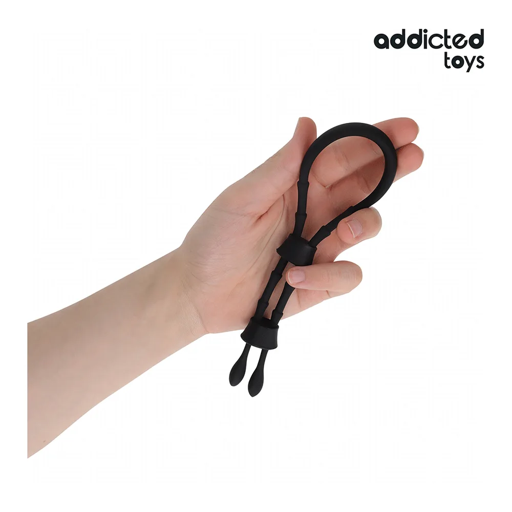 Cockring en silicone noir réglable présenté tenu en mains, formant une boucle avec système d'ajustement par cran