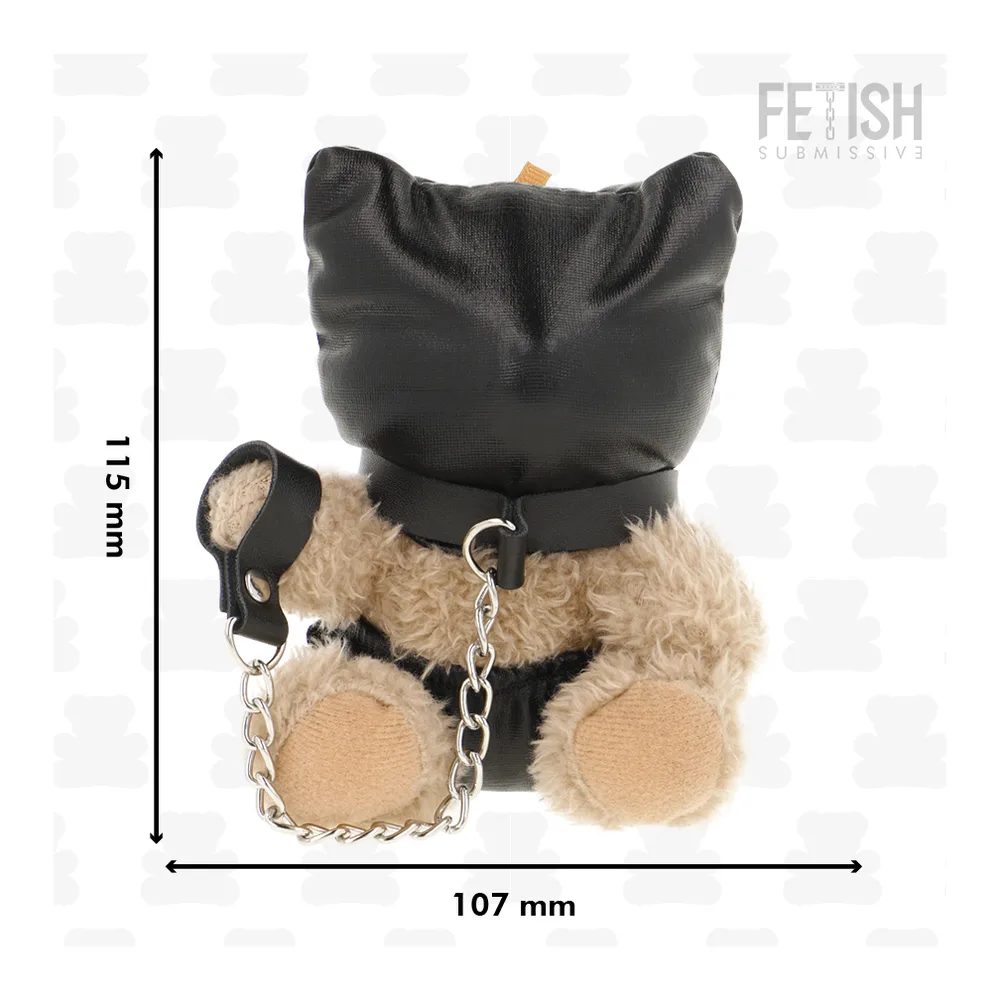 Ours en peluche beige avec tête recouverte d'une housse texturée noire, ceinture de cuir noir, menottes enchaînées aux pattes avant et anneaux métalliques
