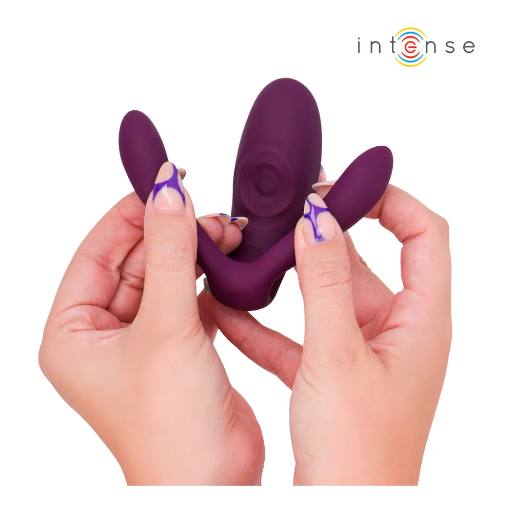 Stimulateur violet en silicone tenu dans deux mains, trois zones de contact distinctes visibles, avec télécommande violette