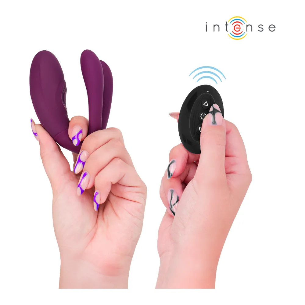 Stimulateur violet en silicone tenu dans deux mains, trois zones de contact distinctes visibles, avec télécommande violette