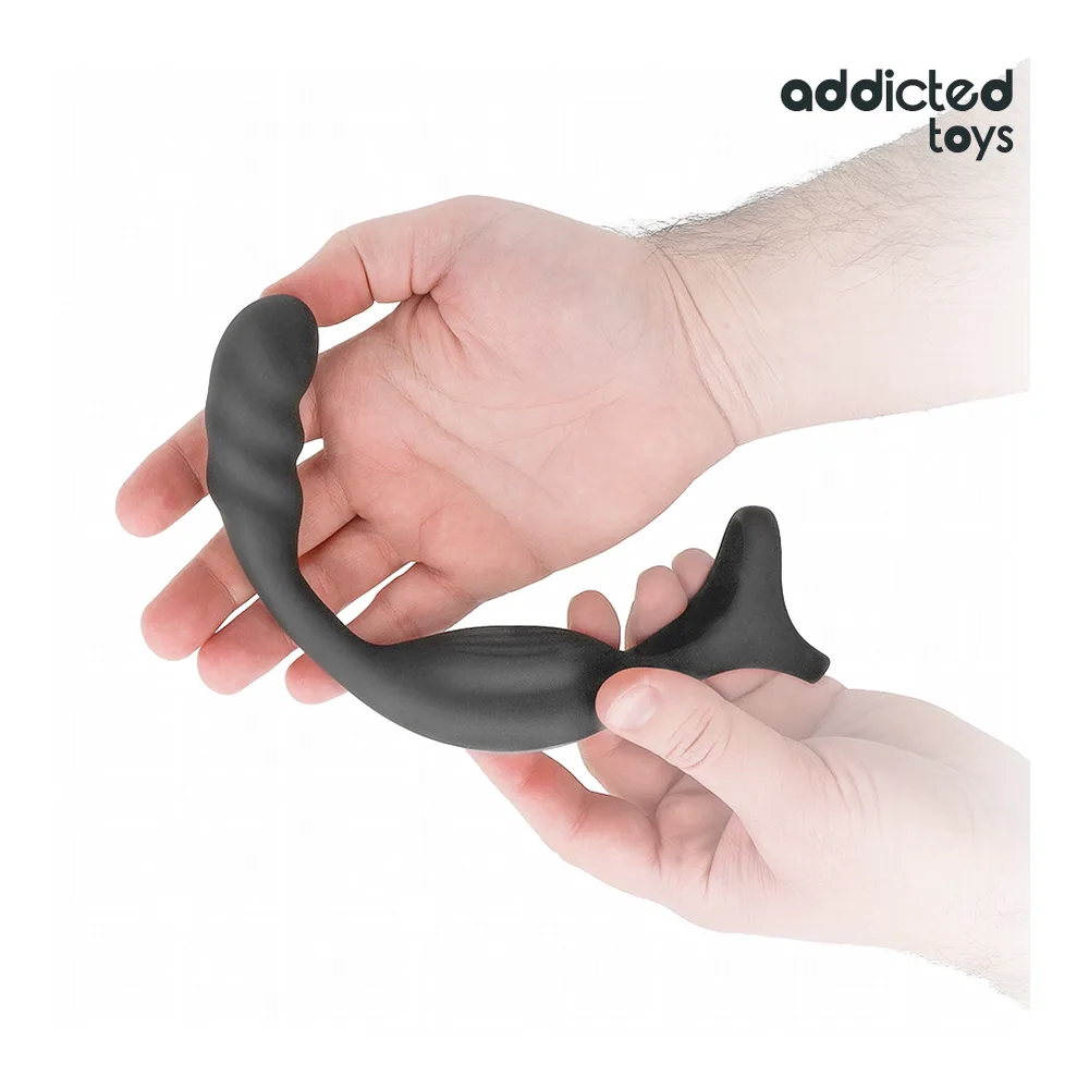 Cockring en silicone noir avec ergot prostatique, tenu dans deux mains sur fond blanc