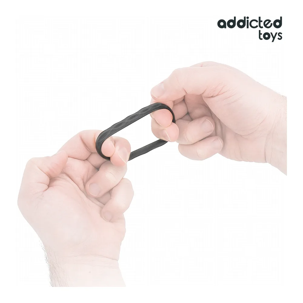Deux mains tenant un cockring noir en silicone extensible, montrant sa flexibilité et sa texture lisse sur fond blanc