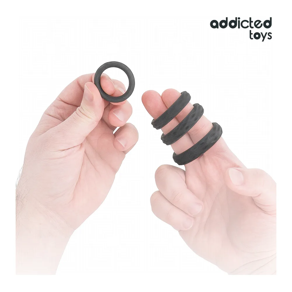 Deux mains tenant un cockring noir en silicone extensible, montrant sa flexibilité et sa texture lisse sur fond blanc