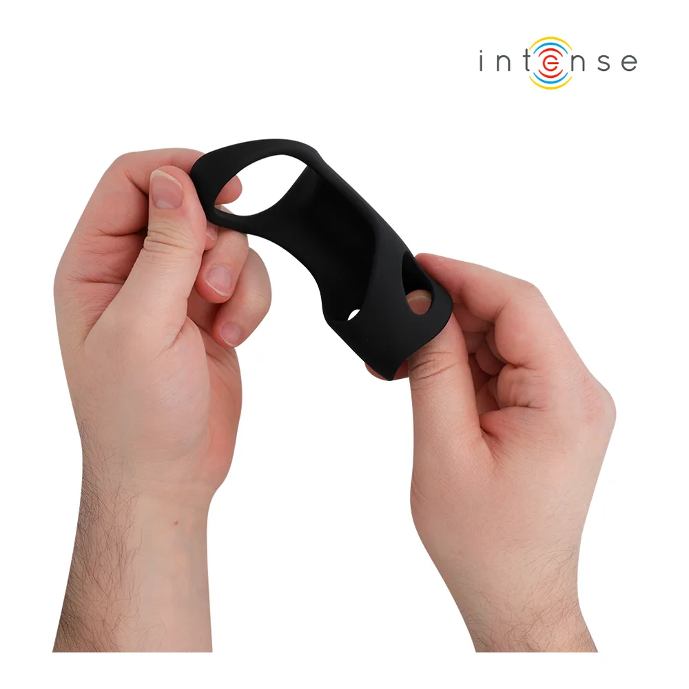 Cockring vibrant noir en silicone extensible, tenu dans deux mains, montrant sa forme arquée avec extension supérieure et orifices de ventilation
