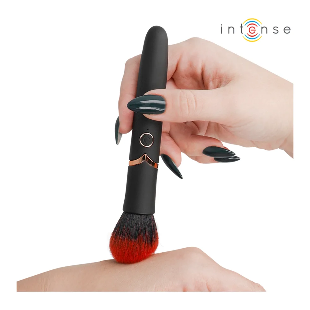 Vibromasseur noir en forme de pinceau, poils rouges et noirs, tenu en main avec bague vibrante grise, logo Intense en haut
