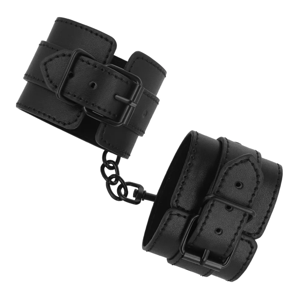 Paire de menottes en cuir végétalien noir avec boucles de réglage, chaîne de liaison et anneau métallique, sur fond blanc