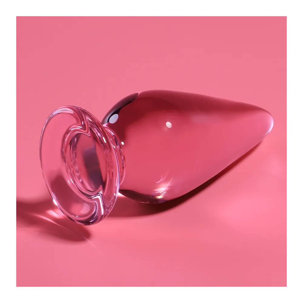 Plug anal en verre borosilicate rose transparent, forme de goutte effilée, base circulaire plate de couleur rose foncé, fond blanc