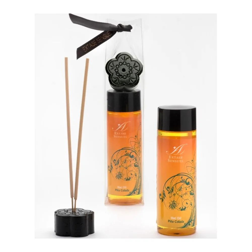 Flacon airless orange avec bouchon noir de l'huile de massage Extase Sensuel, motif floral stylisé, étiquette blanche avec mention Hot Oil Piña Colada, sur fond blanc