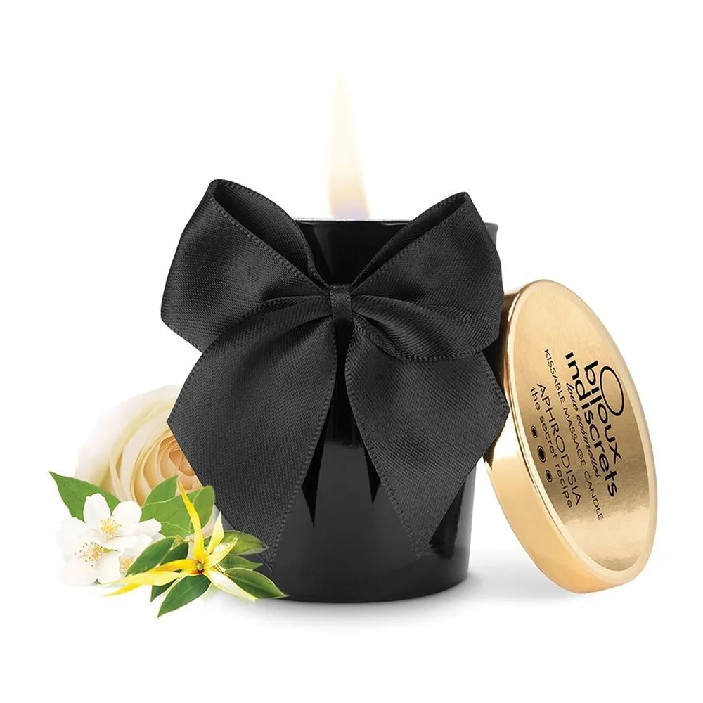 Bougie de massage noire avec nœud gris anthracite et couvercle doré gravé, flamme visible au-dessus du pot sur fond blanc
