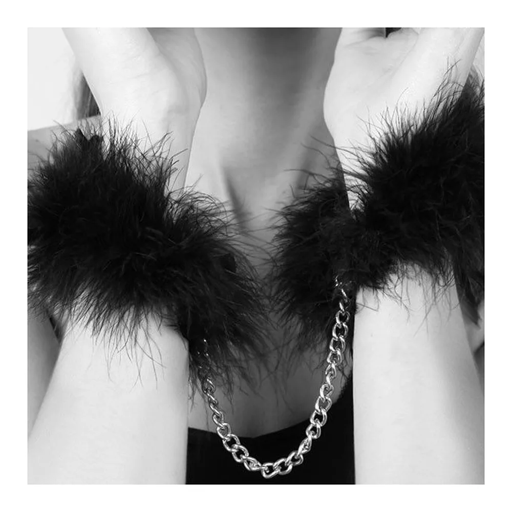 Menottes avec deux manchettes en plumes noires reliées par une chaîne argentée, présentées avec leur boîte de rangement noire