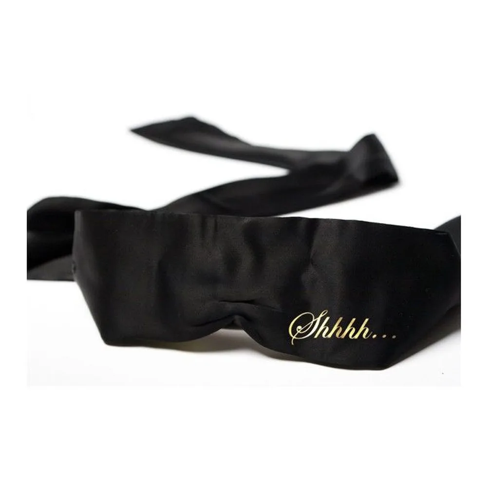 Masque en satin noir avec ruban attaché, imprimé « Shhhh » visible sur le devant, sur fond blanc