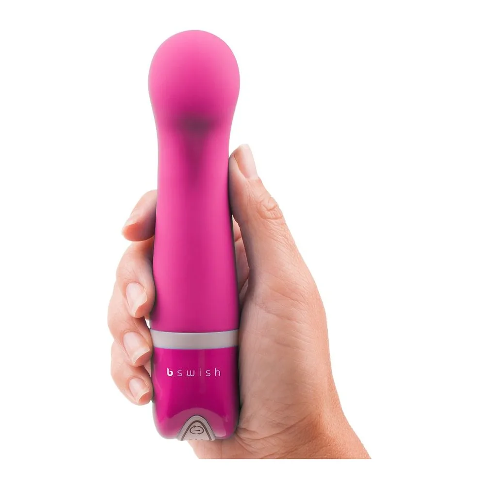 Boîte noire et blanche du vibromasseur Bdesired Deluxe Curve de Swish, avec photo du produit fuchsia en silicone à embout recourbé et anneau blanc de retrait, accompagné d'un petit vibromasseur assorti