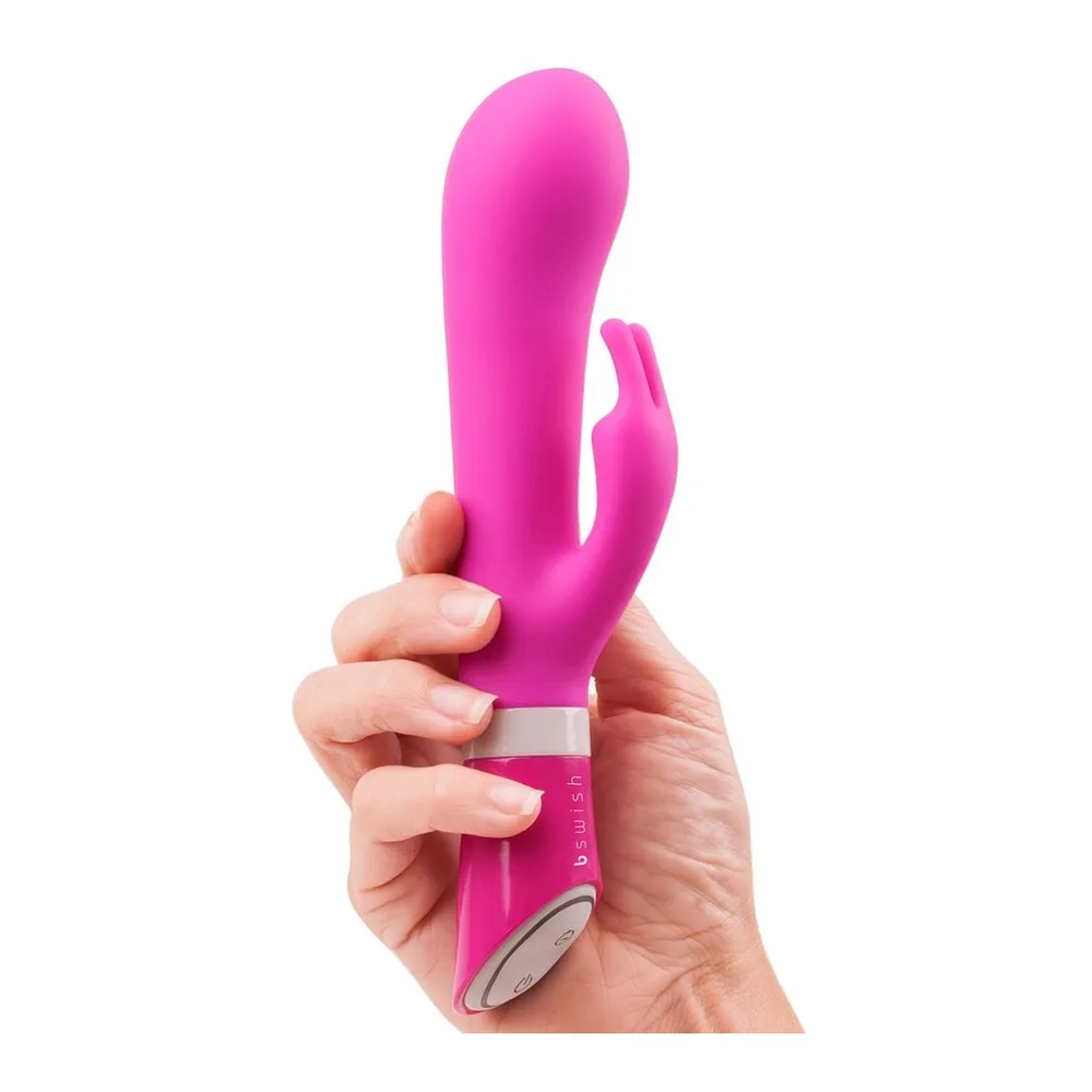 Vibromasseur rabbit rose fuchsia en silicone, tenu en main, avec bras clitoridien articulé et bande blanche au niveau de la base