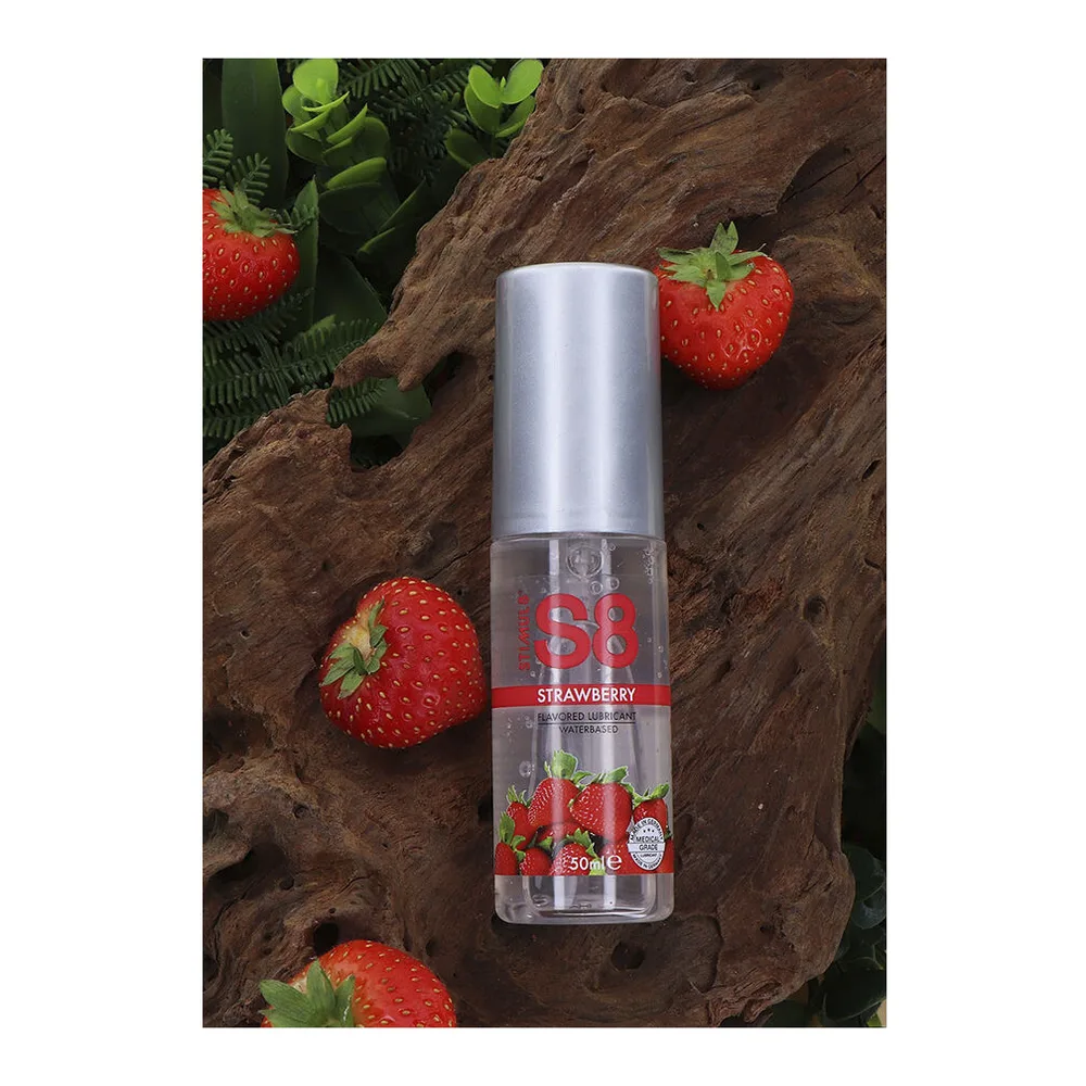 Flacon de 50 ml de lubrifiant comestible à base d'eau parfum fraise, avec capuchon argenté et étiquette blanche ornée de fraises rouges