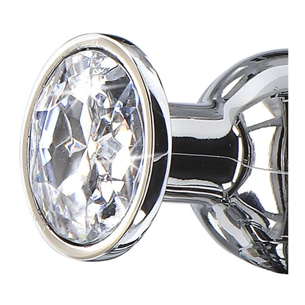 Plug anal en aluminium poli chromé avec base ornée d'un grand cristal taillé transparent, vue de profil sur fond blanc