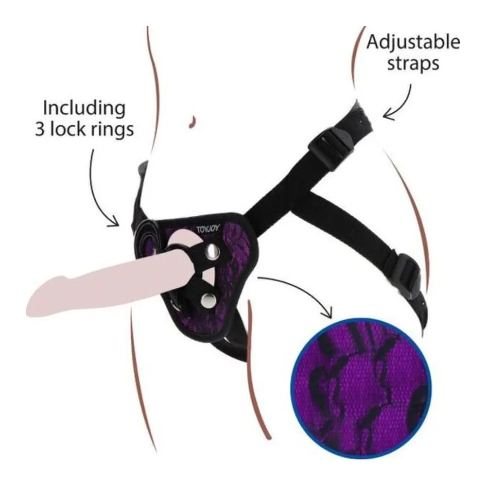 Harnais strap-on noir avec dentelle violette et bleue, ceinture ajustable avec bretelles, incluant 3 anneaux de fixation, illustré en schéma technique avec détail du motif de la dentelle