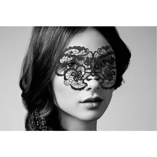 Masque BDSM en cuir noir posé sur un drap sombre