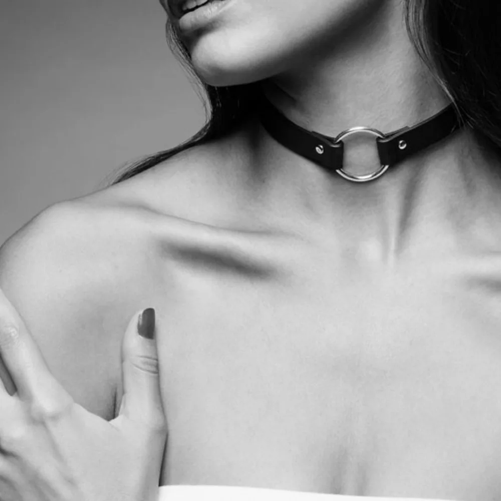Collier ras du cou noir en matière synthétique avec anneau de métal doré en façade et passant de chaîne, clous argentés et boucle d'ajustement noire