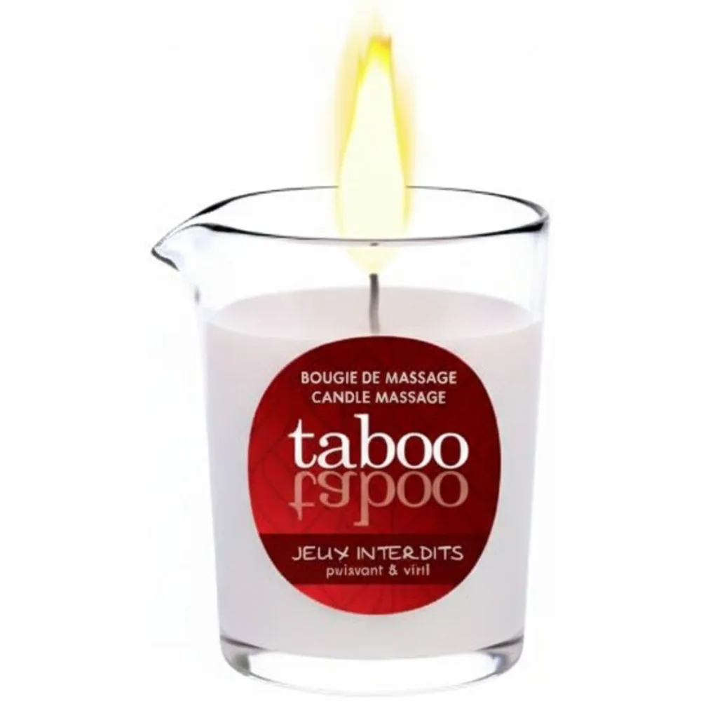 Bougie de massage allumée dans un pot en verre transparent, cire blanche avec flamme jaune vive, étiquette rouge foncé Taboo Jeux Interdits visible sur le devant