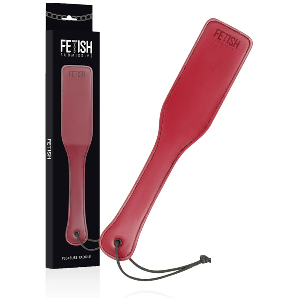 Fouet rose fuchsia avec lame plate et surpiquée, poignée ergonomique, cordon noir à la base, présenté à côté de son emballage noir Fetish Submissions