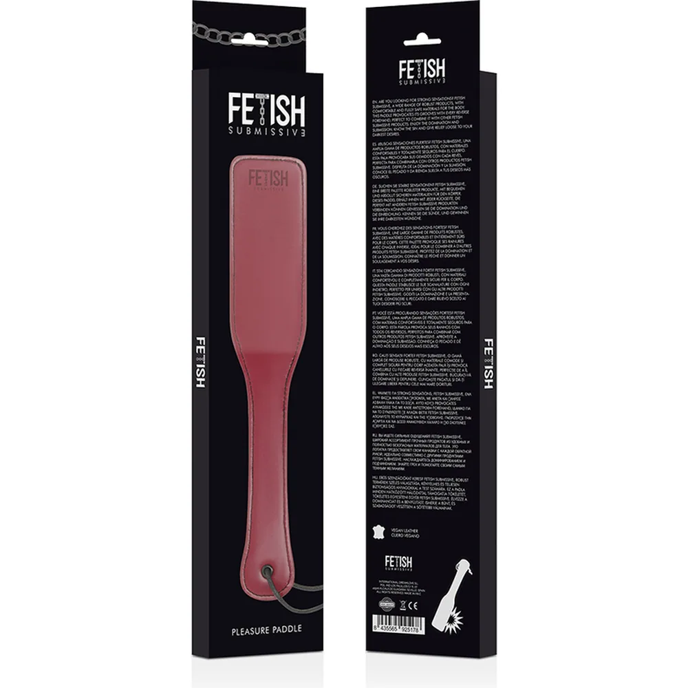 Fouet rose fuchsia avec lame plate et surpiquée, poignée ergonomique, cordon noir à la base, présenté à côté de son emballage noir Fetish Submissions