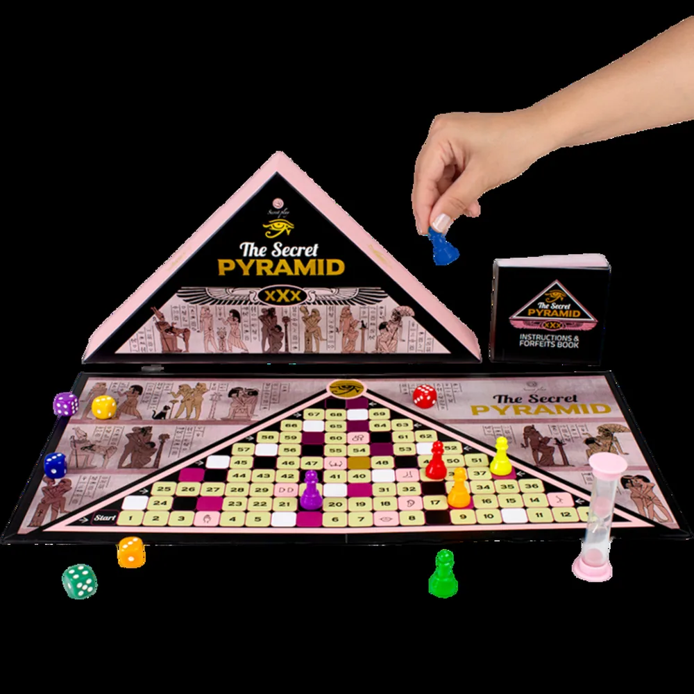 Boîte de jeu en forme de pyramide triangulaire, face noire avec inscriptions dorées « The Secret Pyramid » et motifs égyptiens, dos rose avec symbole doré, fond blanc