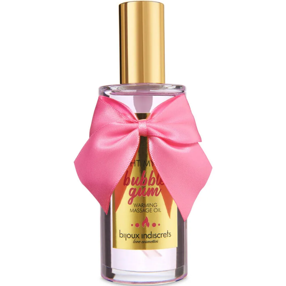Flacon de verre contenant une huile de massage rose pâle, bouchon doré, orné d'un nœud rose vif, étiquette jaune mentionnant bubble-gum et huile de massage chauffante