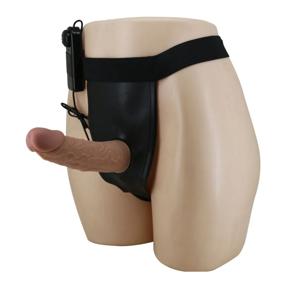 Slip beige avec harnais noir réglable, gode en silicone marron clair attaché sur le côté, moteur de vibration noir fixé à l'arrière